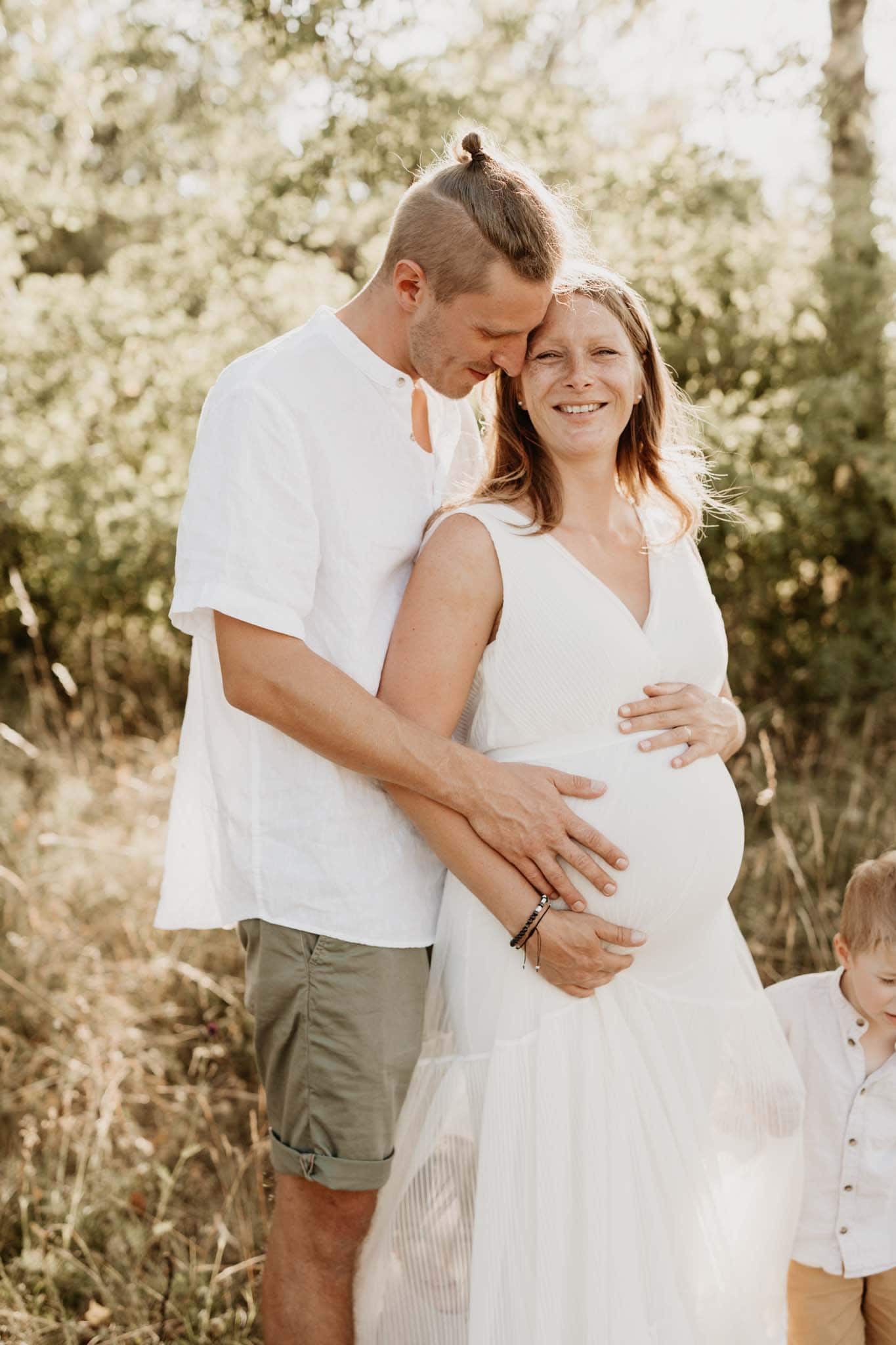 Mann und seine schwangere Frau umarmen sich beim Babybauch Outdoorshooting