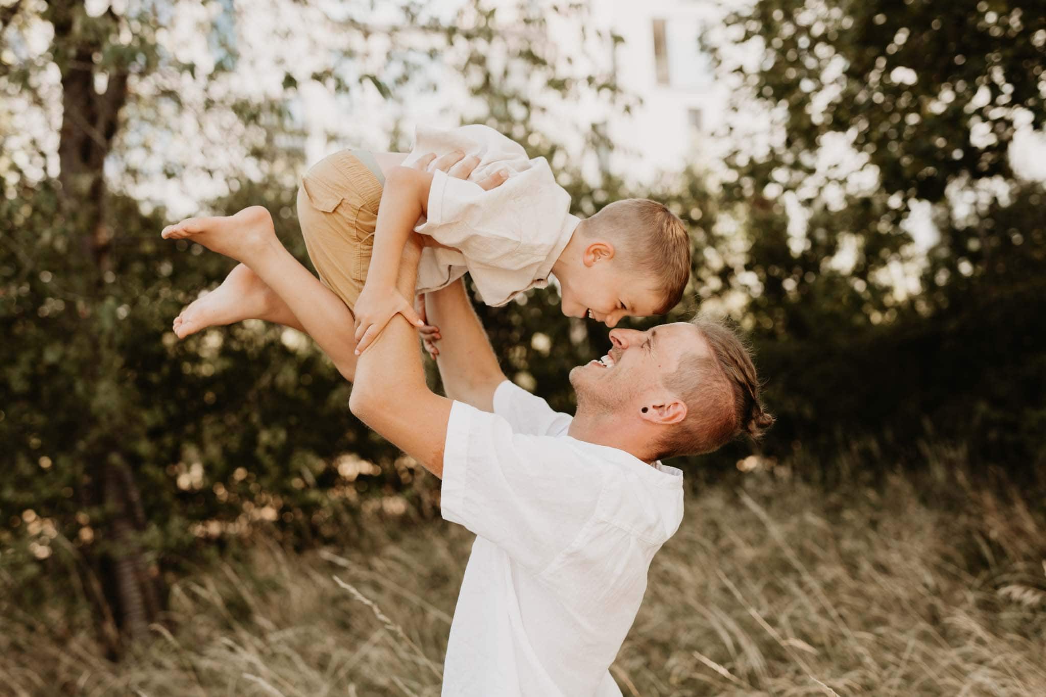 Beim Babybauchshooting hebt Vater den Sohn hoch in die Luft