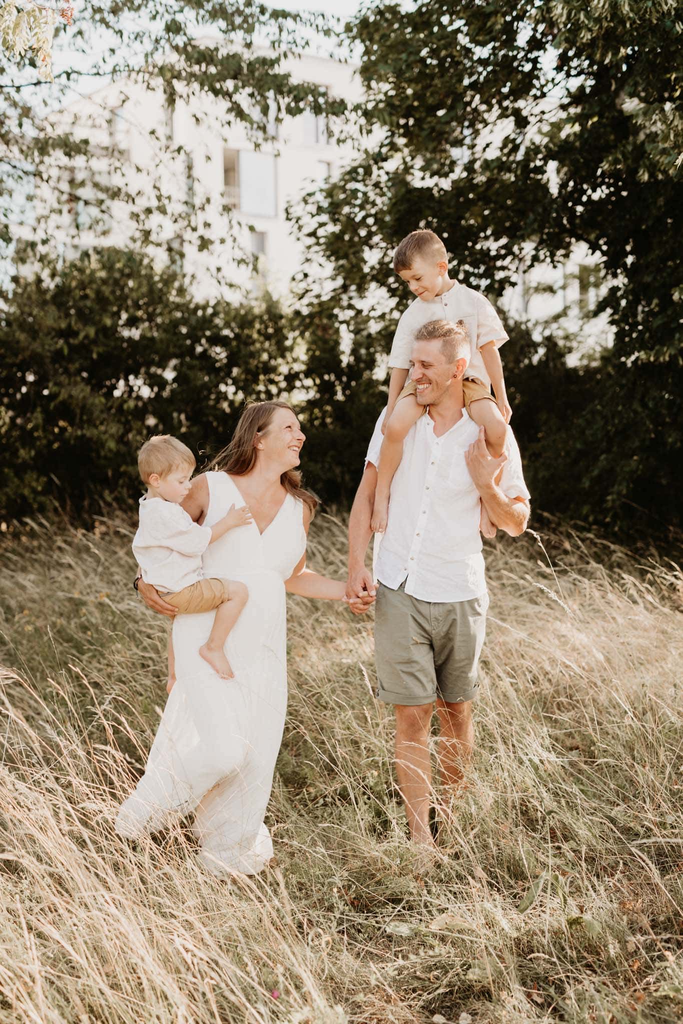 Familiefoto mit schwangeren Frau läuft lachend durch die Wiese