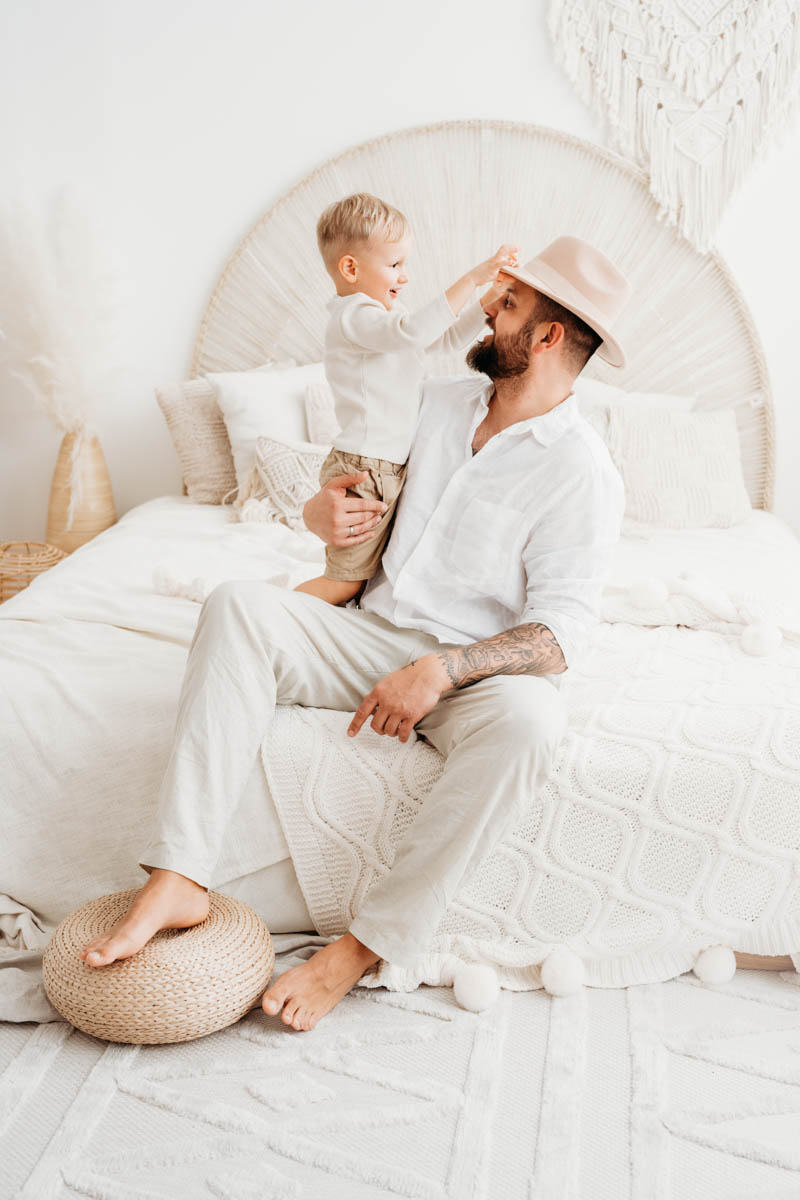 Beim Babybauchshooting setzt Junge seinem Vater einen Hut auf
