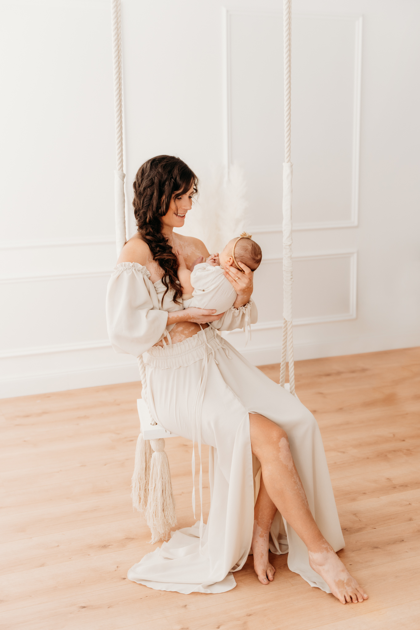 Mama sitzt mit Baby auf Vintage Schaukel