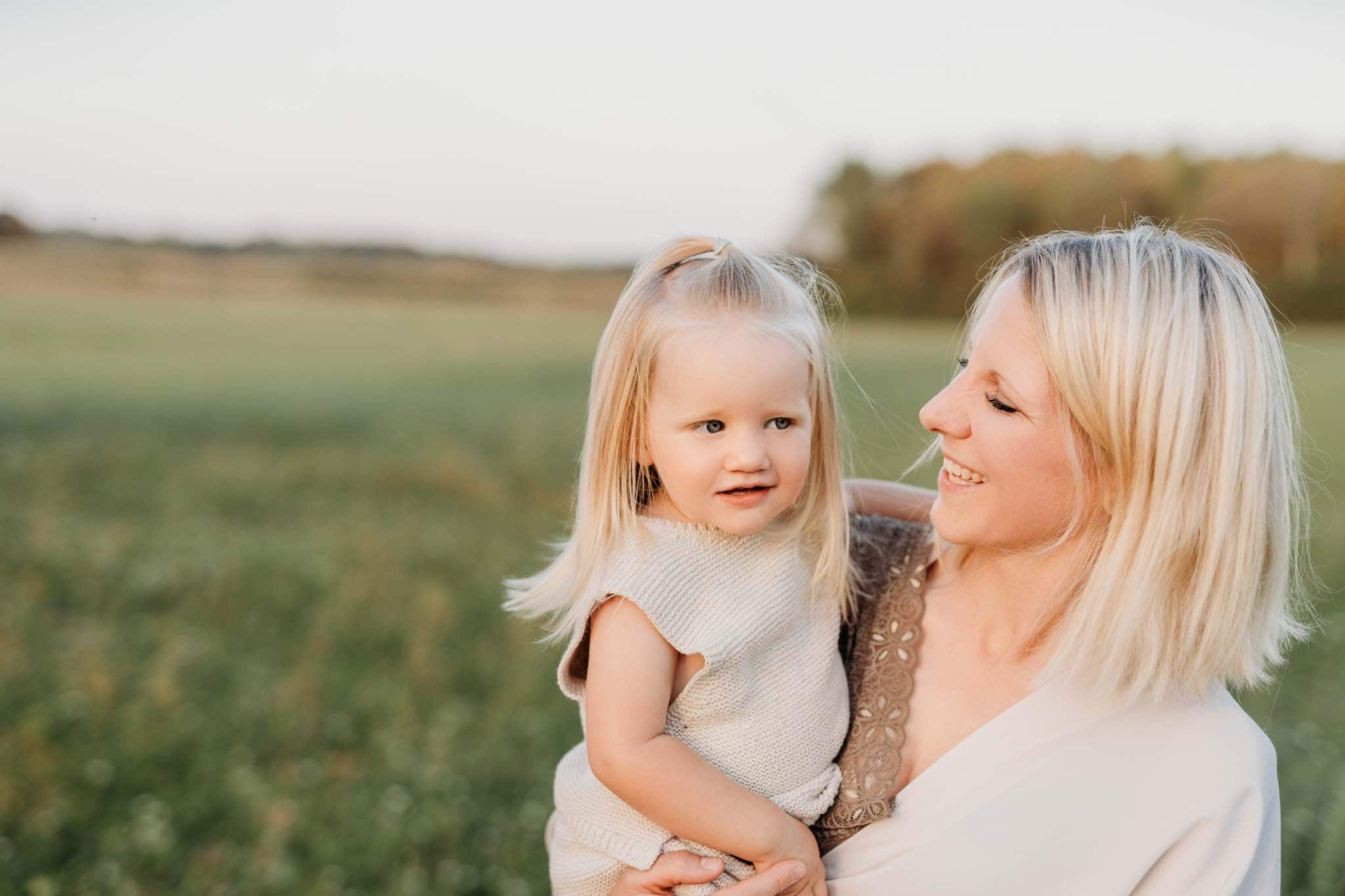 Portrait von Mama und kleiner Tochter beim Familien Fotoshooting München in der Natur Mama hält Tochter liebevoll auf dem Arm