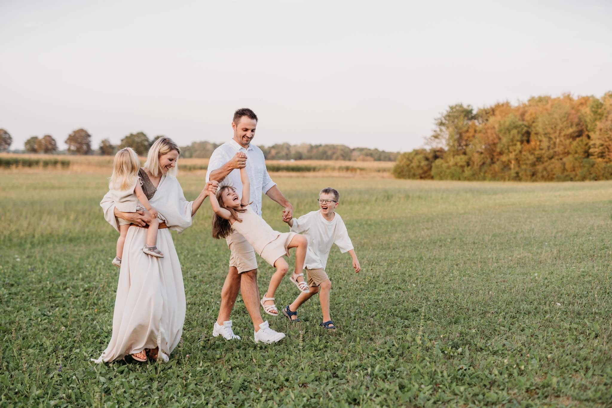 Beim Familienshooting outdoor läuft Familie mit Kindern durch die Wiese Familie läuft durch die Wiese und spielt Müller Müller Sackerl