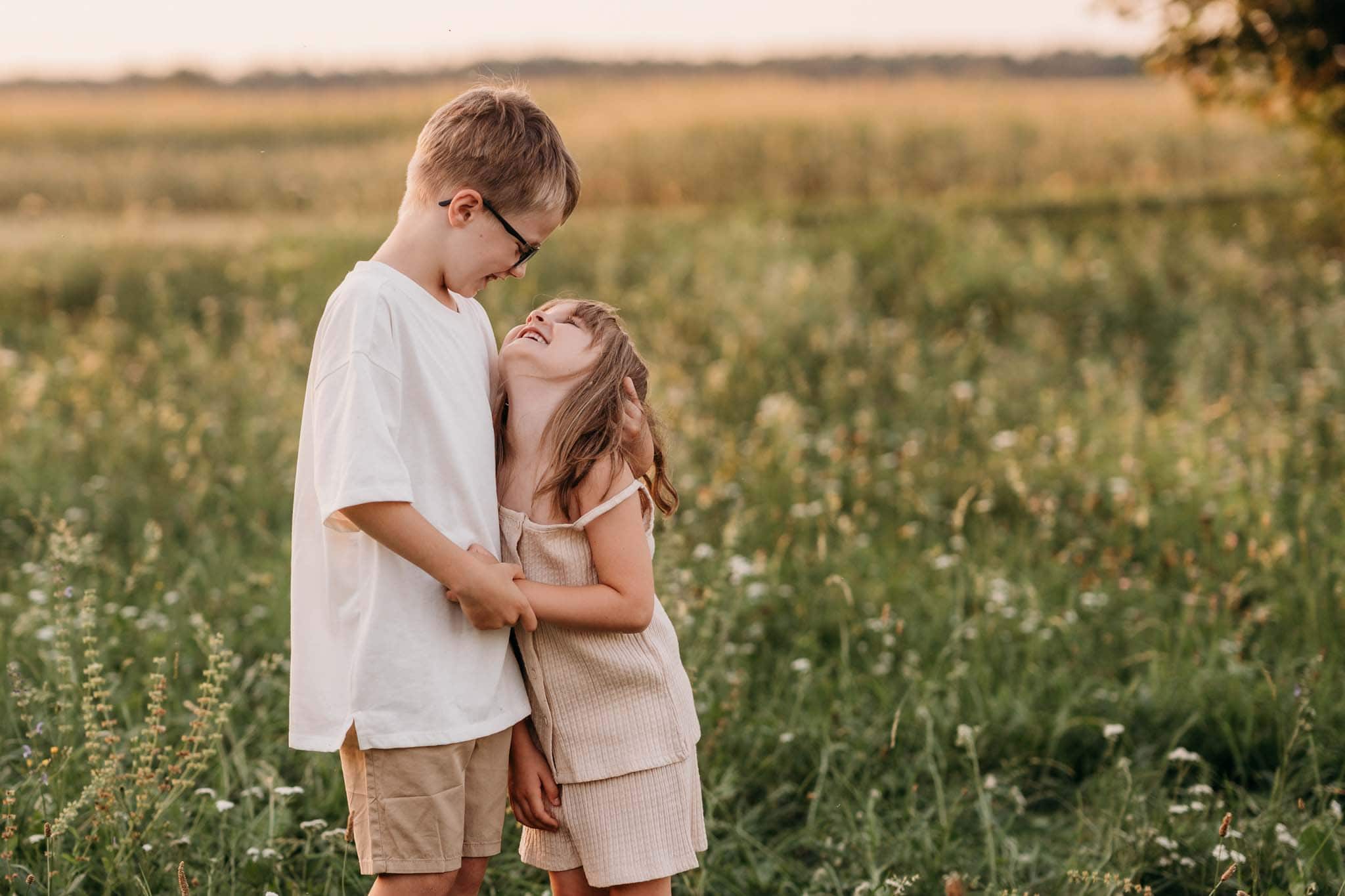 Familienshooting mit Geschwistern auf einer Wiese in München Zwei Kinder und die kleine Schwester schaut den großen Bruder in die Augen
