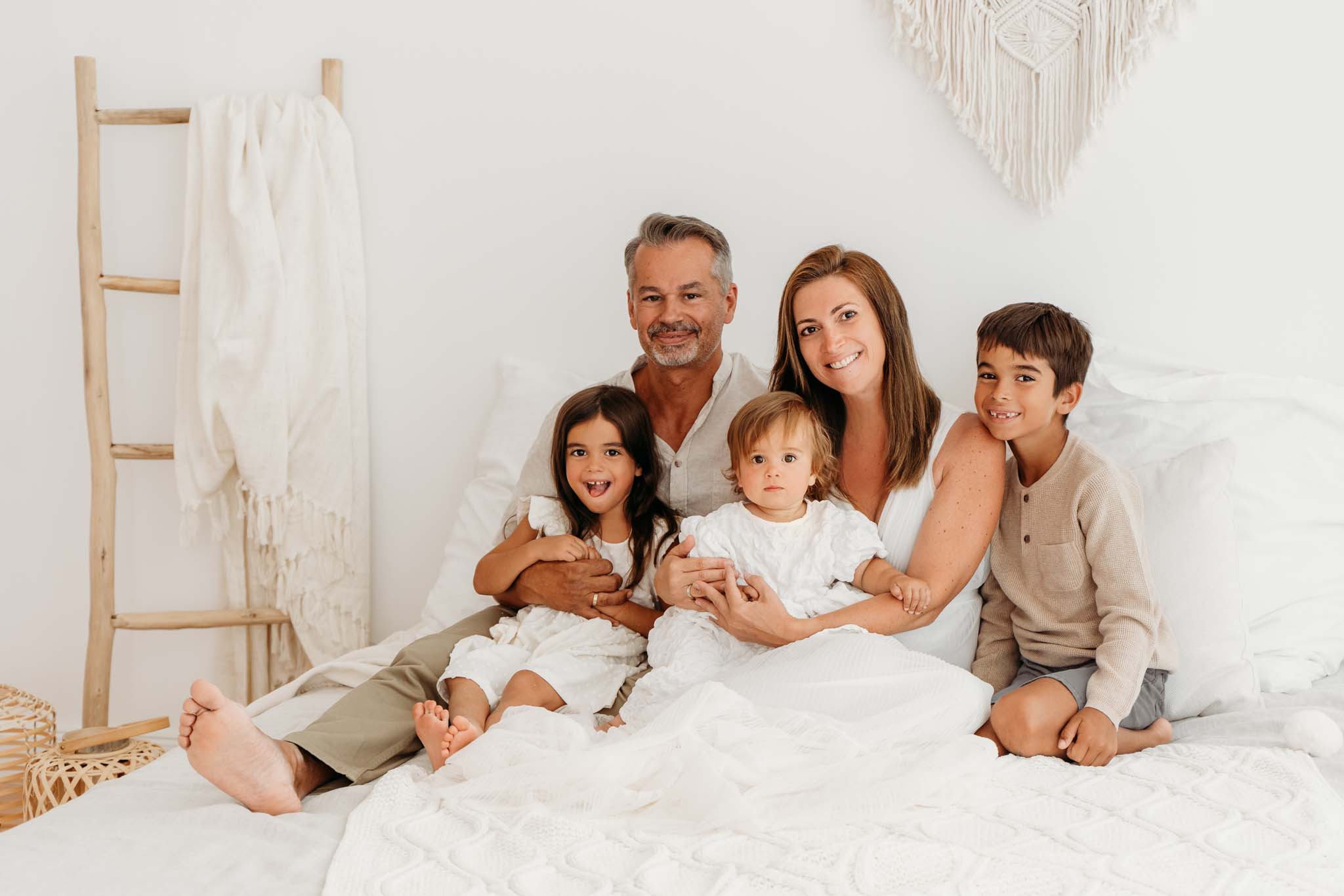 Familie kuschelt am Familienbett im Fotostudio München - Familienfotografie Familienfotografie kuschelnd im Studio auf Bett