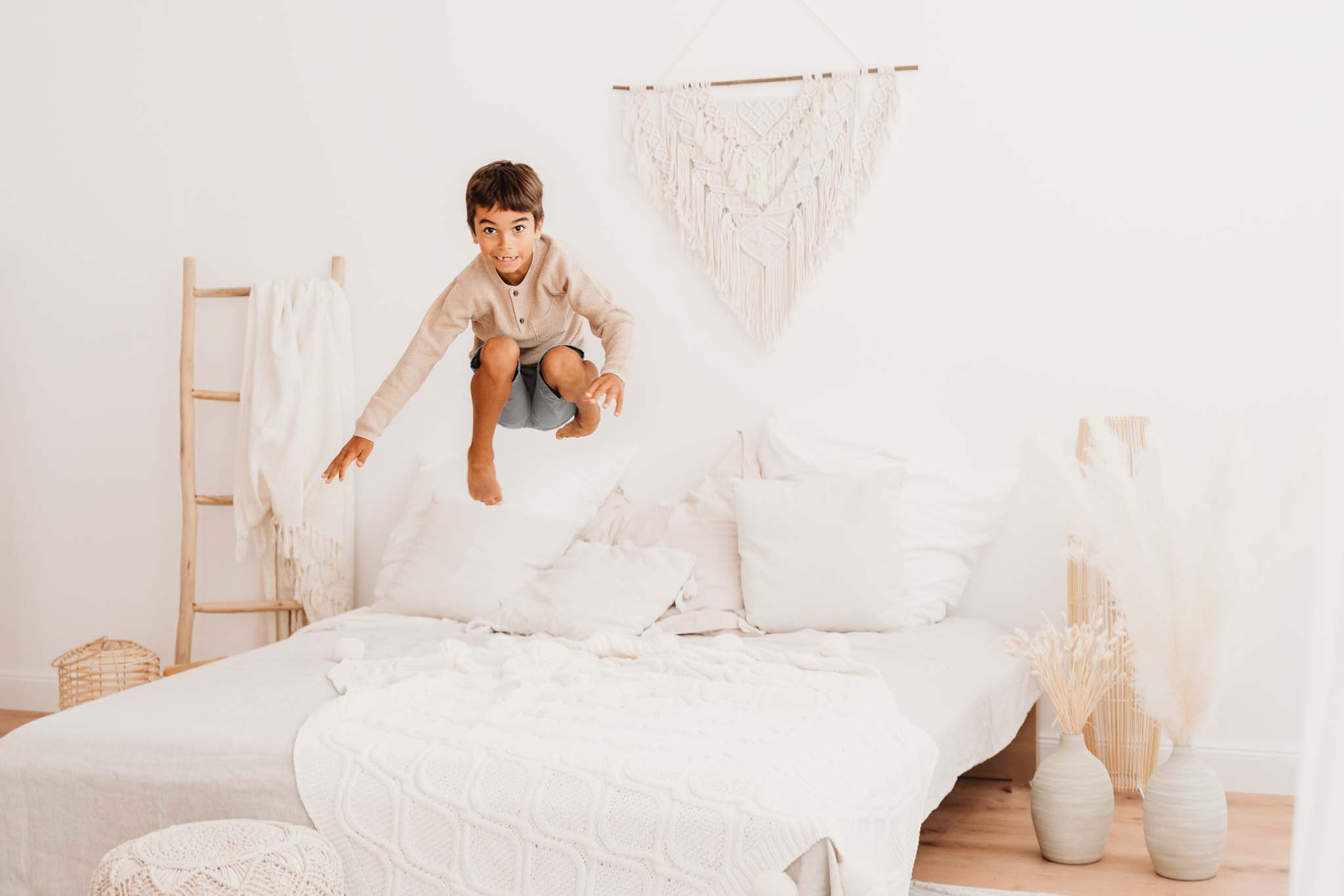 Junge springt am Familienbett beim Familienshooting Junge springt am Familienbett beim Familienshooting