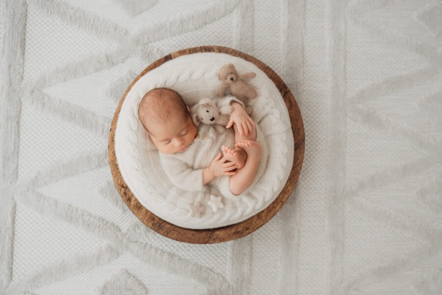 Neugeborenes in Holzschale mit Teddybären beim Fotoshooting München